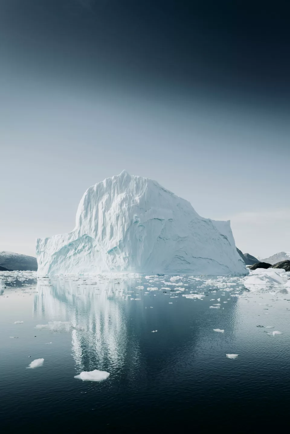 Grand iceberg blanc se reflétant dans des eaux sombres et calmes