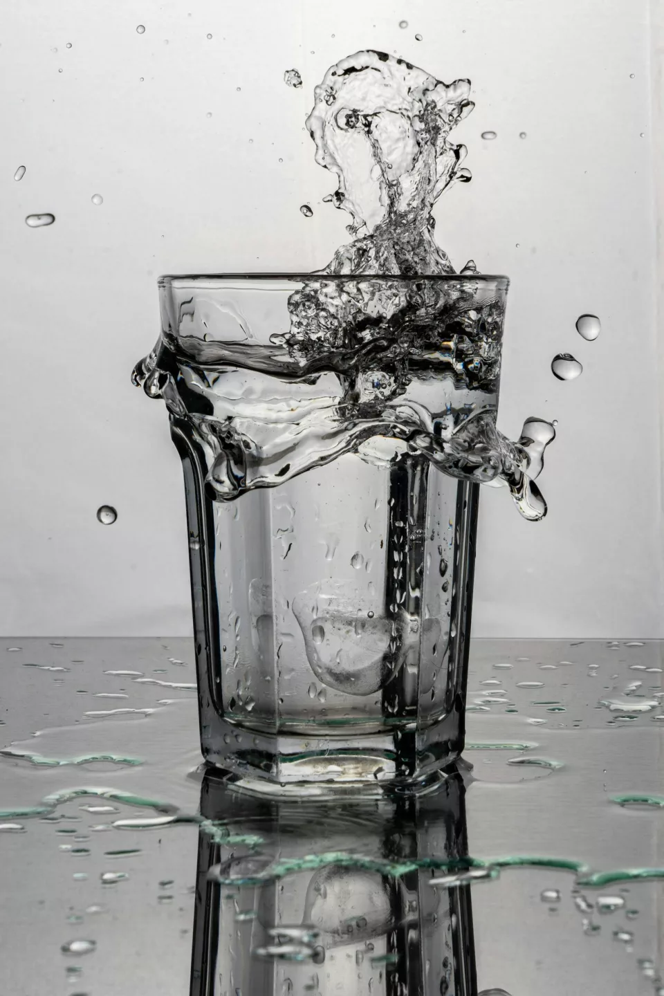 Verre transparent rempli d'eau, posé sur une surface claire