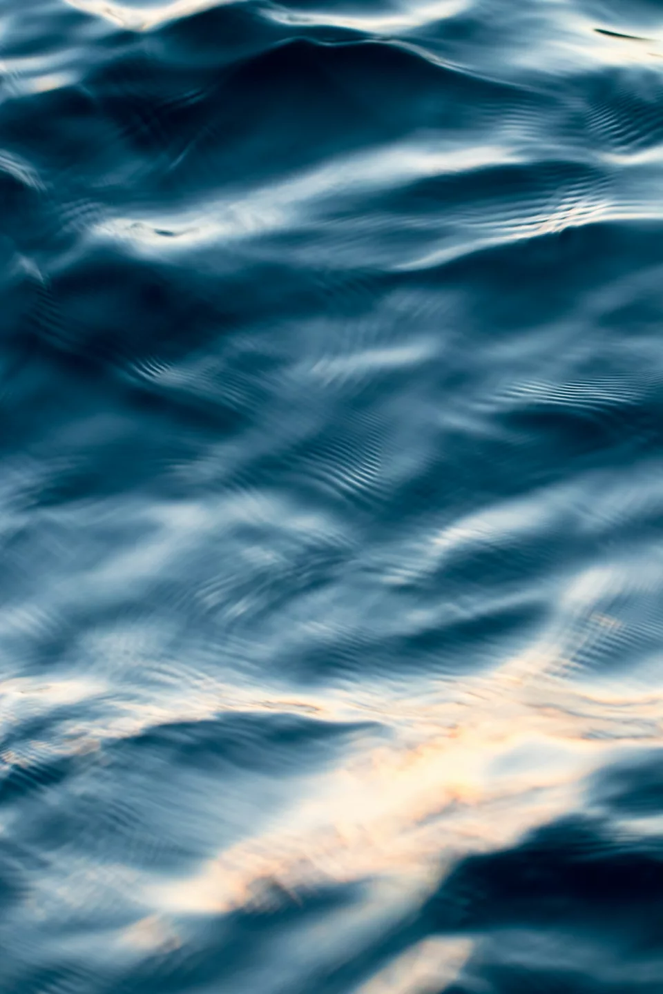 Eau bleu sombre parcourue d'ondulations et de reflets dorés