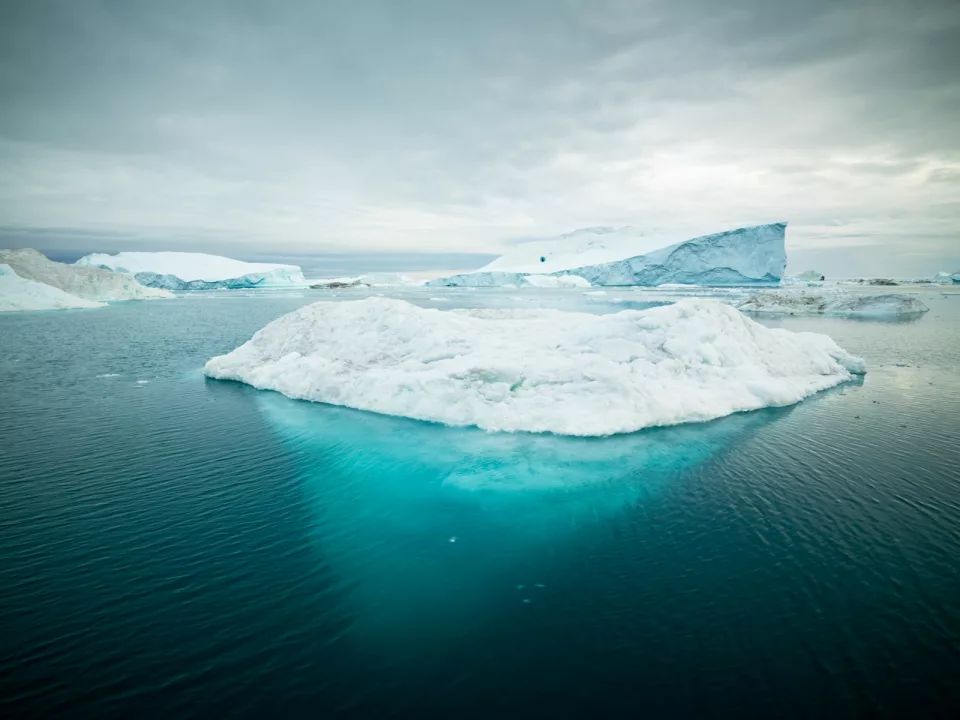 Iceberg émergeant d'une mer froide sous un ciel pâle