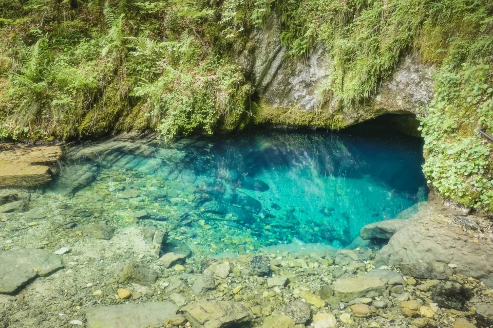 Eau bleue et limpide s'engouffrant dans l'ouverture d'une grotte
