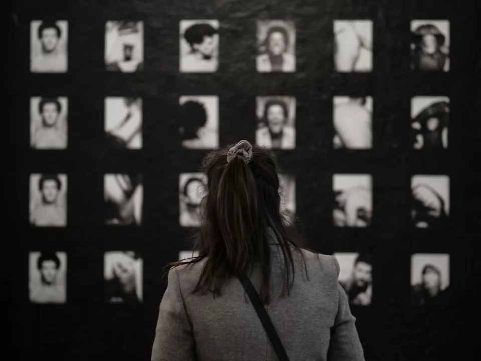 Personne en manteau gris debout devant un mur d'images en noir et blanc